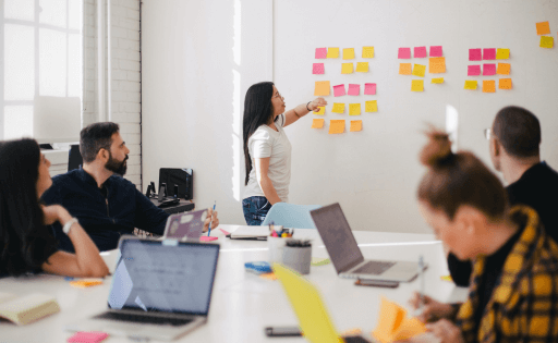 People in a meeting putting sticky notes on a whiteboard